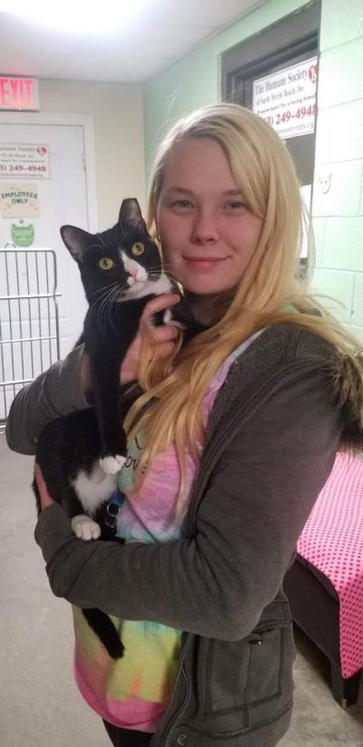 Smiling person holding a black and white cat