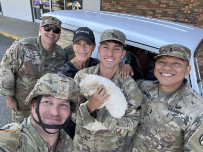 Blanco the cat being held by military personnel