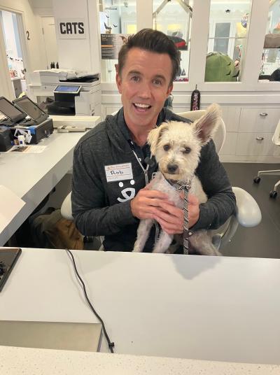 Rob McElhenney with a dog in his lap at the front desk of Best Friends in Los Angeles