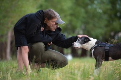 Two people outside with Rosita the dog, one person petting the top of her head