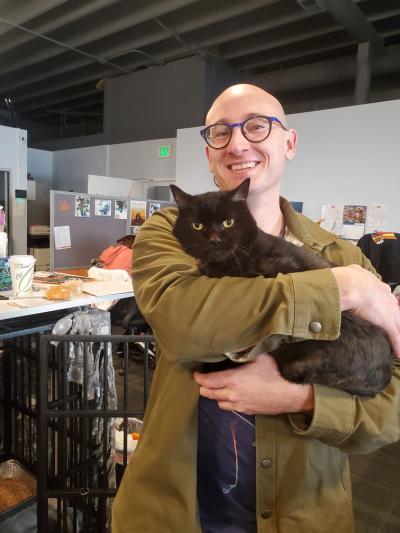 Bryce smiling and holding Fossey the cat