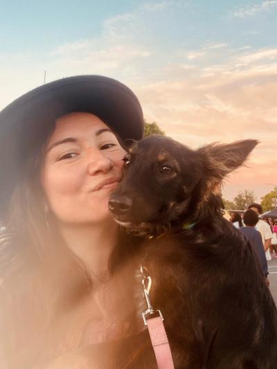 Stoic the dog being held by Diana, who is smiling and wearing a hat