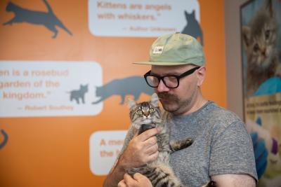 Foster Tyler Lisonbee looking down at the brown kitten he's holding in his arms to his chest