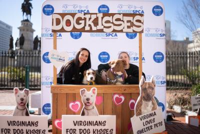 Two people and dogs at a doggie kissing booth at the no-kill event in Virginia