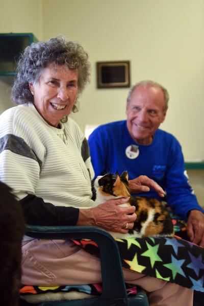 Brenda and Marty Winnick sitting on a bench with a calico cat