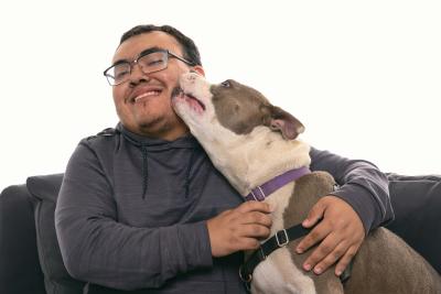 Kenny Popovich getting kissed by Pebbles the dog