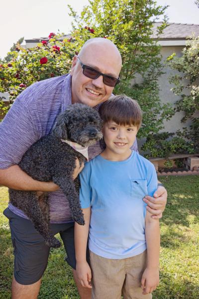 Zoey the dog with two smiling members of her new family, one an adult and one child