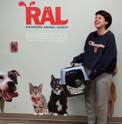 Delila the cat in a carrier being adopted by a smiling person from RAL