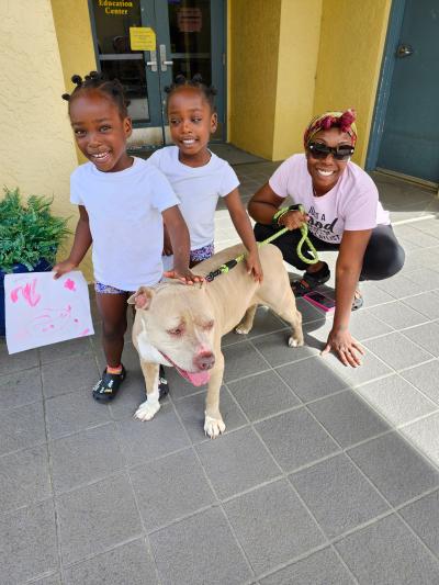 Person with two kids and a tan dog, all smiling