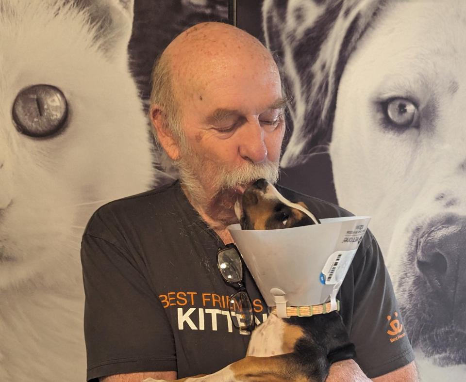 Volunteer Steve Pack holding a puppy wearing a protective cone