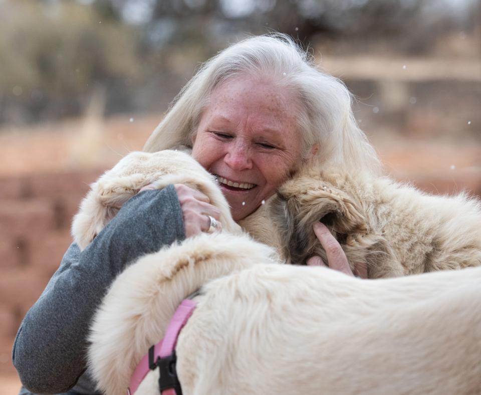 Val Hardin smiling and hugging Anna and Racer the dogs