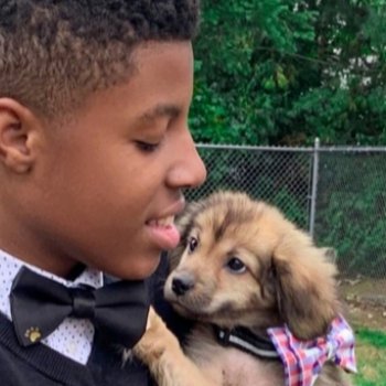 Smiling person holding a puppy outside