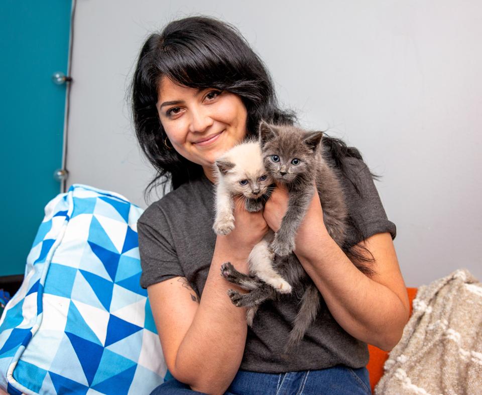 Smiling person holding two tiny kittens