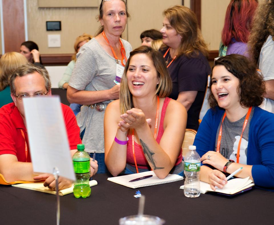 Smiling people sitting around a table with paper and pens in front of them on the table