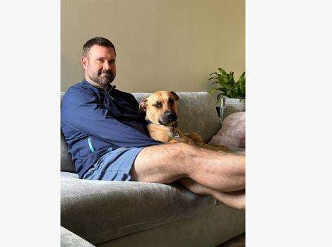 David Reilly sitting on a couch with Rex the dog